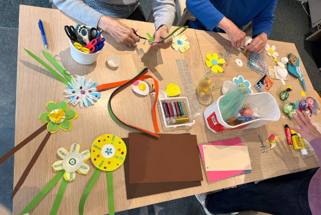 Tisch mit Bastelutensilien und 2 paar Händen die kreativ sind