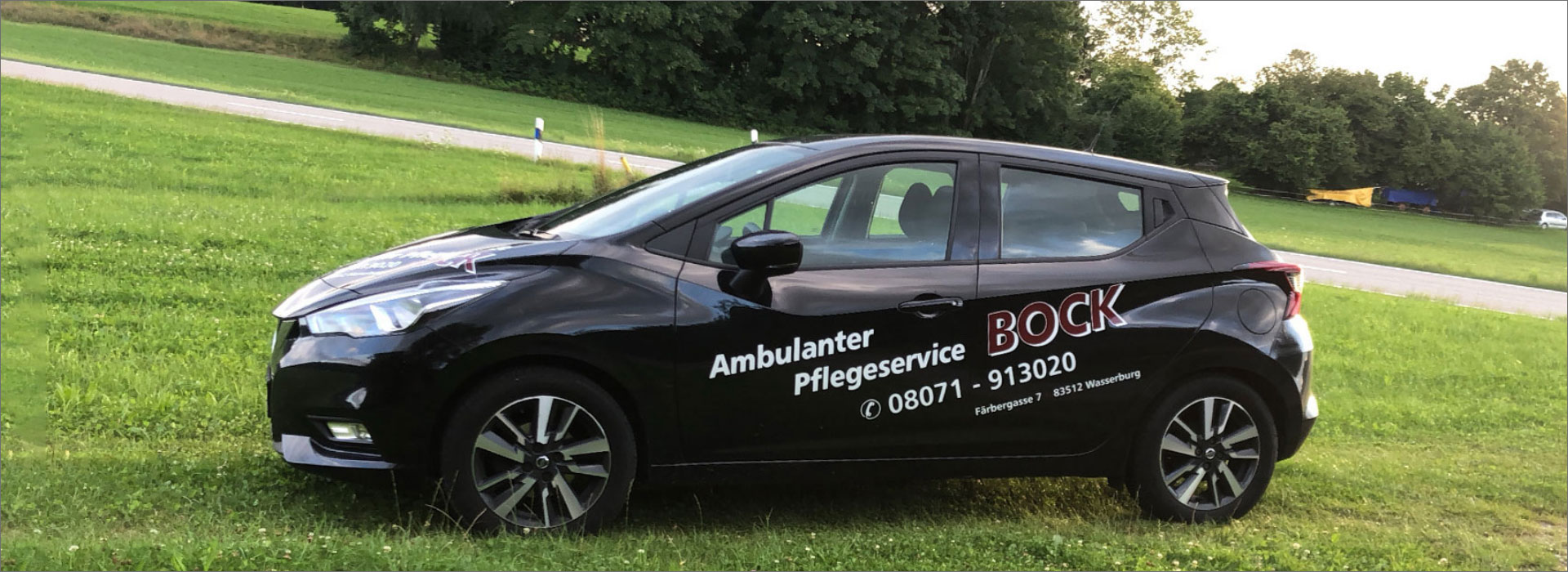 pflegeservice Bock auto mit Beschriftung steht auf einer Wiese